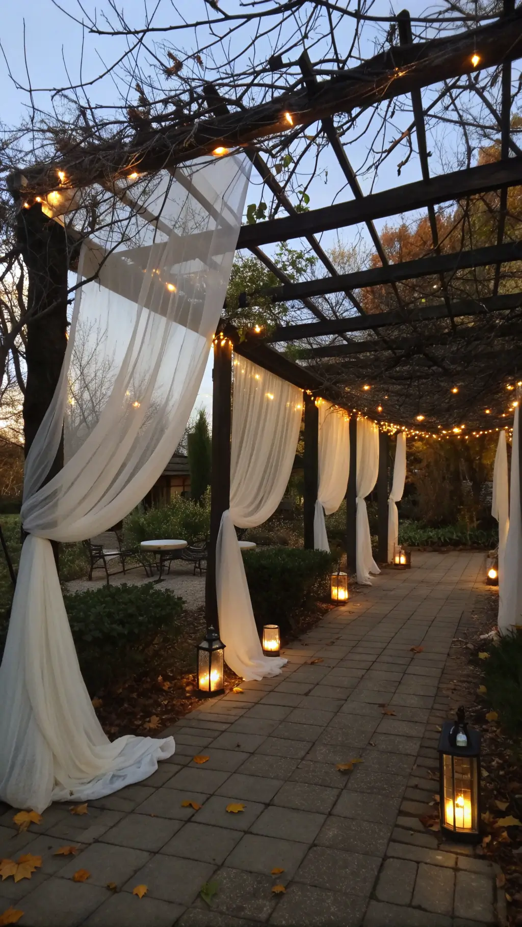 Twilight image of a garden pergola decorated with white fabric ghosts, fairy lights, autumn vines, and paper lanterns.